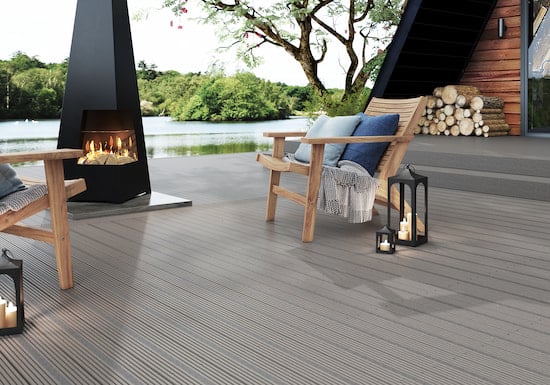picture of composite decking installed with two garden chairs and an outdoor fireplace